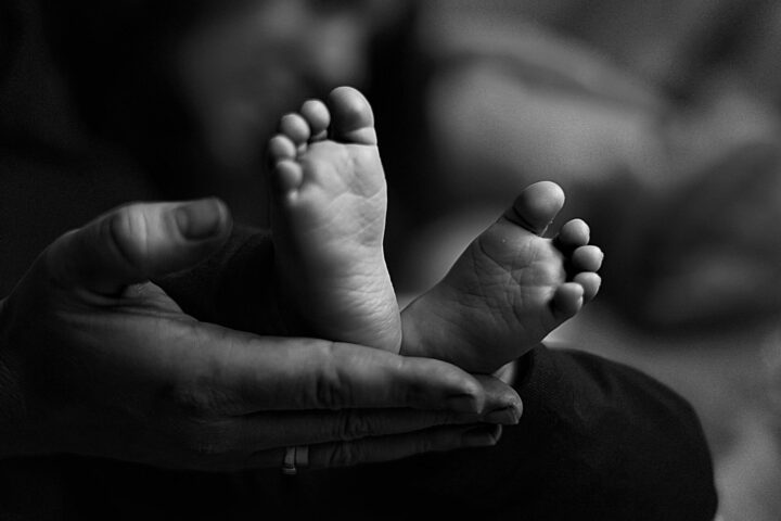 Black and white photography of newborn's small feet, symbolizing the fragility of life created through in vitro technologies